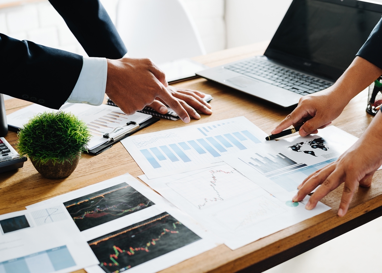 Professionals Pointing At Charts On Desk